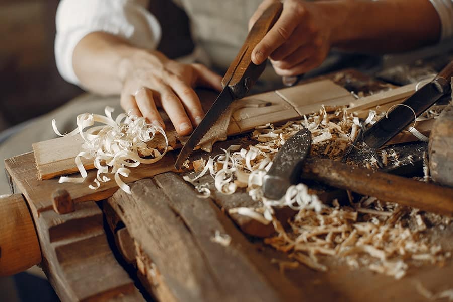 Artigiano che lavora il legno a mano con lo scalpello