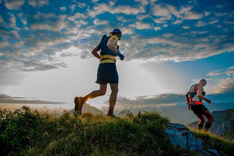 Due trail runner su una cresta di montagna al tramonto