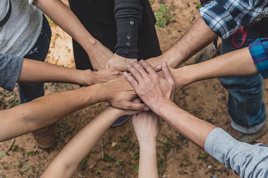 Mani unite al centro di un gruppo di persone